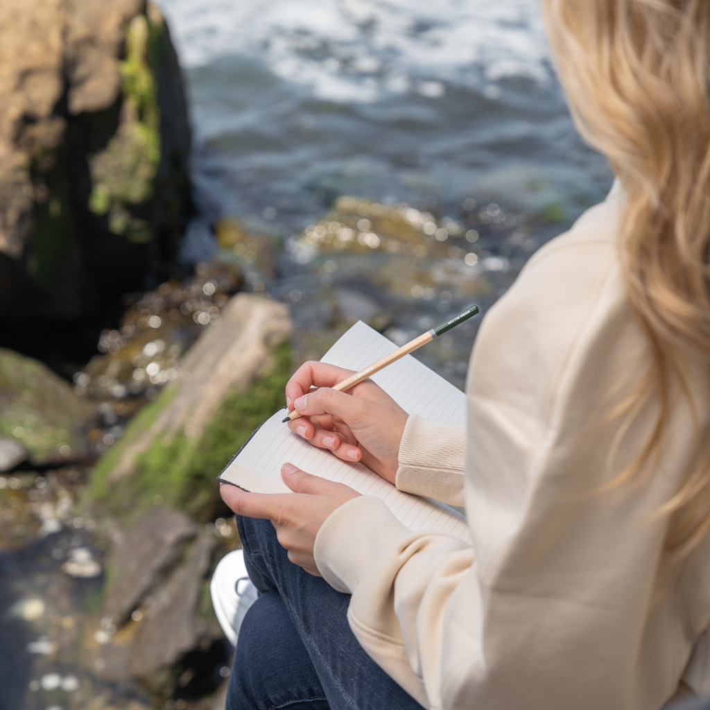 A woman journaling by the seaside.